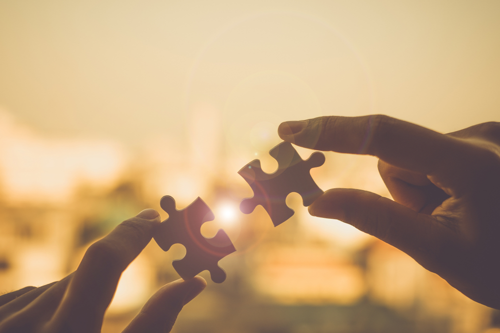 A close-up of hands connecting a puzzle piece